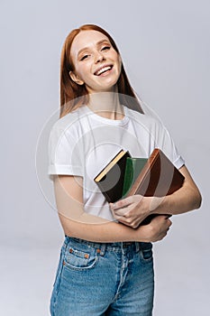 Portrait of smiling young woman college student holding books and looking at camera.