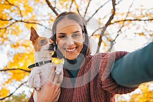 Portrait of smiling young woman with dog making selfie