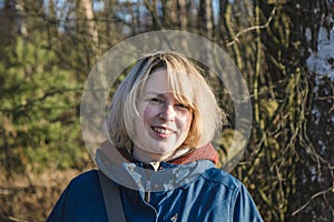 Portrait of a smiling young woman at the edge of the forest in early spring