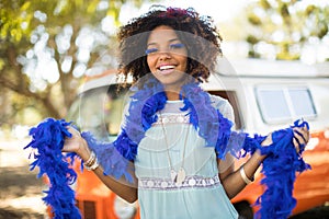 Portrait of smiling young woman with feather fur wearing artificial eyelashes