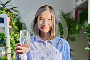 Portrait of smiling young woman with glass of water posing at home