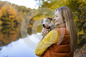 Portrait of a smiling young woman kissing a dog in a field. Dog lover stylish