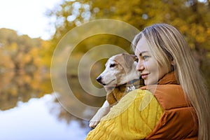 Portrait of a smiling young woman kissing a dog in a field. Dog lover stylish