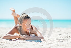 Portrait of smiling young woman laying on beach