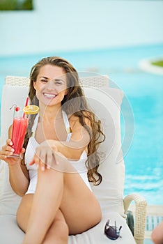Portrait of smiling young woman laying on sunbed