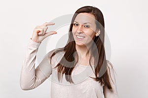 Portrait of smiling young woman in light clothes gesturing demonstrating size with workspace isolated on white wall