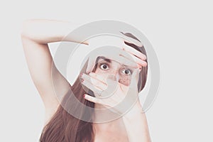 Portrait of smiling young woman making a hand frame isolated on white background