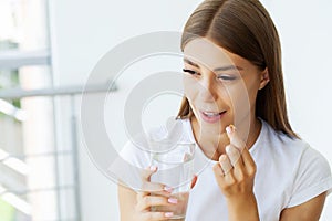 Portrait of smiling young woman with Omega 3 fish oil capsule