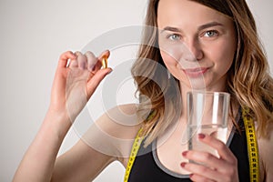 Portrait of smiling young woman with Omega 3 fish oil capsule