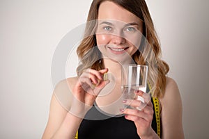 Portrait of smiling young woman with Omega 3 fish oil capsule