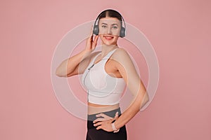 Portrait of smiling young woman posing with headphones against pink backdrop