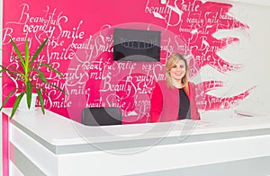 Portrait of smiling young woman with receptionist in dentist's office