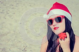 Portrait of a smiling young woman in Santa Claus hat and sungla