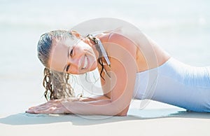 Portrait of smiling young woman in swimsuit laying on sea shore