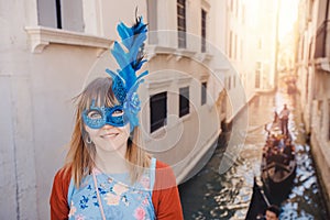 Portrait smiling young woman in Venice in Venetian blue mask background canal and gondolier. Concept travel