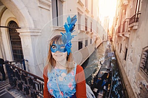 Portrait smiling young woman in Venice in Venetian blue mask background canal and gondolier. Concept travel