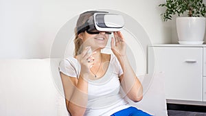 Portrait of smiling young woman in VR headset watching movie on sofa