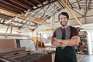 Smiling woodworker standing in his workshop by a bench saw photo