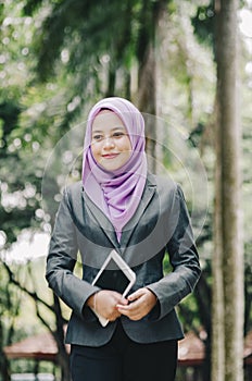 Portrait of smilling young professional muslimah businesswoman holding a tablet