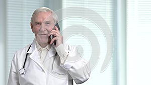 Portrait of smilng senior grey hair physician with smartphone.