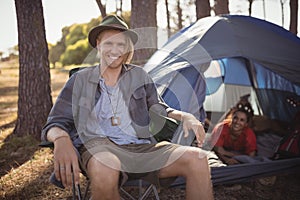 Portrait of smling man sitting on chair by tent