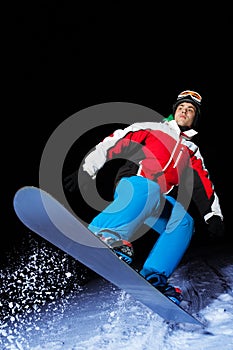 Portrait of snowboarder jumping at night