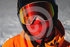 Portrait of a snowboarder. Ski goggles and ski helmet on a man looking at the camera, close-up. Holidays in the ski