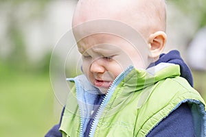 The portrait of a sobbing toddler against the background of nature