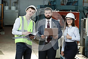 Portrait of a solid businessman with his secretary and factory engineer holding laptop, talking about factory financial report