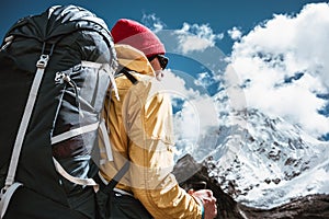 Portrait of solo hiker with traveling backpack standing in front of massive snowy mountains. Tourist among himalayas mountain