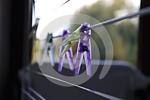 a portrait of some colorful washingpins hanging on a laundry rack without clothes. they are used to hang and dry wet clothing on a