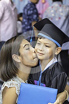 Portrait son graduated from kindergarten and mother kissing