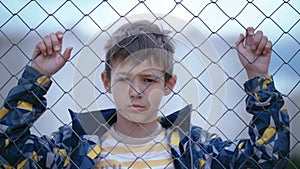 Portrait of a Sorrowful, Pouting Boy Gazing Through the Fence