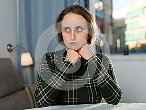 Portrait of sorrowful woman sitting at home