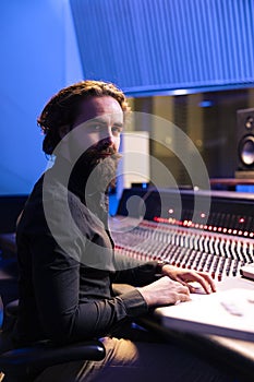 Portrait of sound engineer working with audio console and digital software