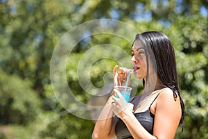 Portrait of South American woman, young, pretty, brunette with leather top, drinking a blue hailstorm with a straw. Concept beauty