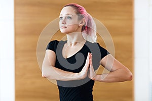 Portrait of sport attractive woman with pink hair making the Namaste gesture, practicing yoga, working out, wearing sportswear in