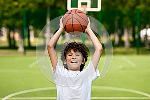 Portrait of sportive curly boy throwing basket ball