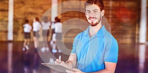 Portrait of sports teacher writing on clipboard