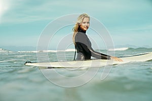 Portrait, sports and woman in ocean with surfboard for sports, travel or vacation in summer. Sky, fitness and exercise