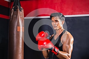 Portrait of Sportsman muay thai boxer fighting in gym, muscular handsome boxing man fighter with boxing bag