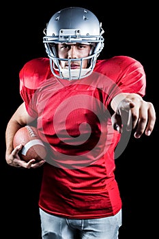 Portrait of sportsman pointing while holding American football