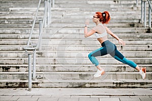 Portrait of sportswoman with fit body jumping and running on stairs background. Woman doing hardcore cardio training