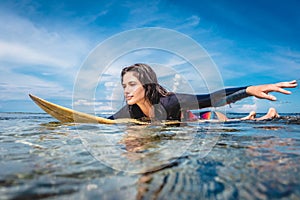 portrait of sportswoman in wetsuit on surfing board in ocean at Nusa dua Beach