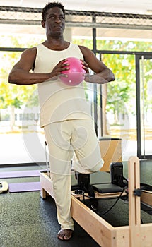 Portrait of sporty african american man with ball in a pilates class in gym