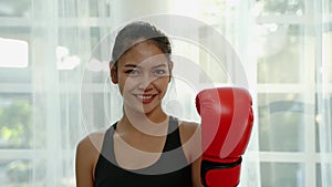 Portrait, sporty Asian woman wearing boxing gloves smiling confidently, health concept, exercise, confidence