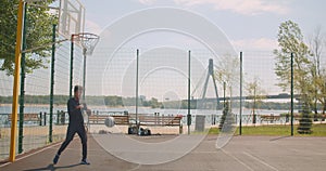 Portrait of sporty attractive African American male basketball player throwing a ball into a hoop and celebrating with