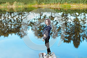 Portrait of sporty beautiful adult brunette woman the fall city park posing near blue lake with autumn trees reflections