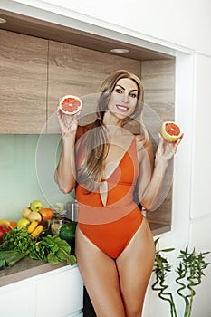 Portrait of a sporty girl with a grapefruit in her hands in the kitchen with fresh vegetables and fruits. The concept of