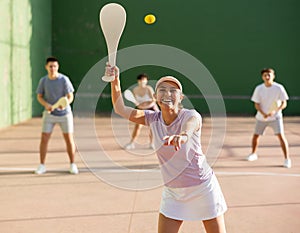 Portrait of sporty girl playing paleta fronton on outdoor court, ready to hit ball. Healthy and active lifestyle concept